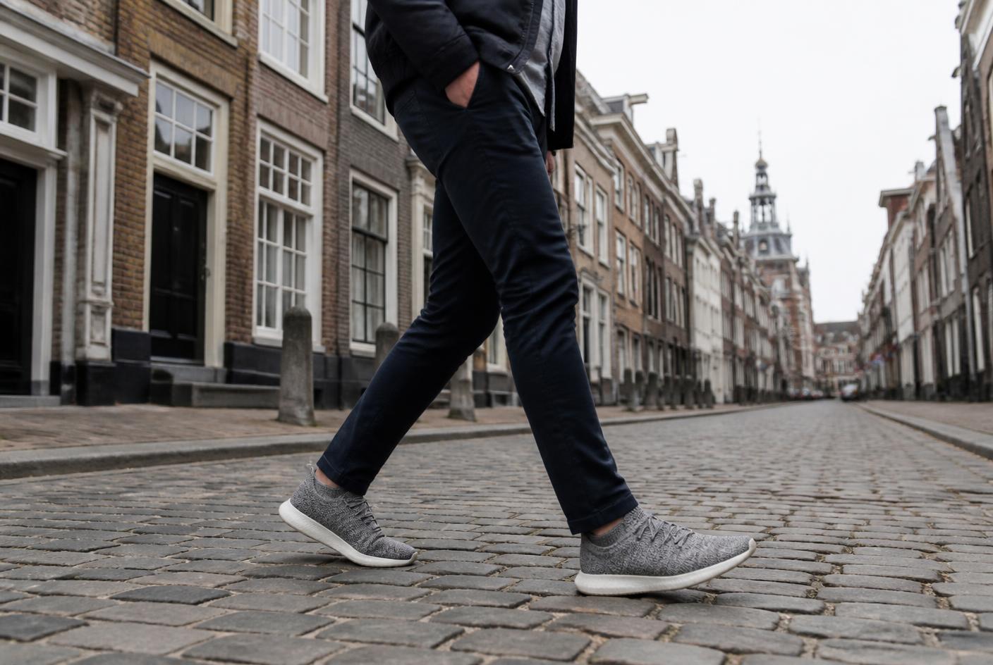 Passant marchant sur une rue pavée européenne, chaussé de la chaussure intelligente grise
